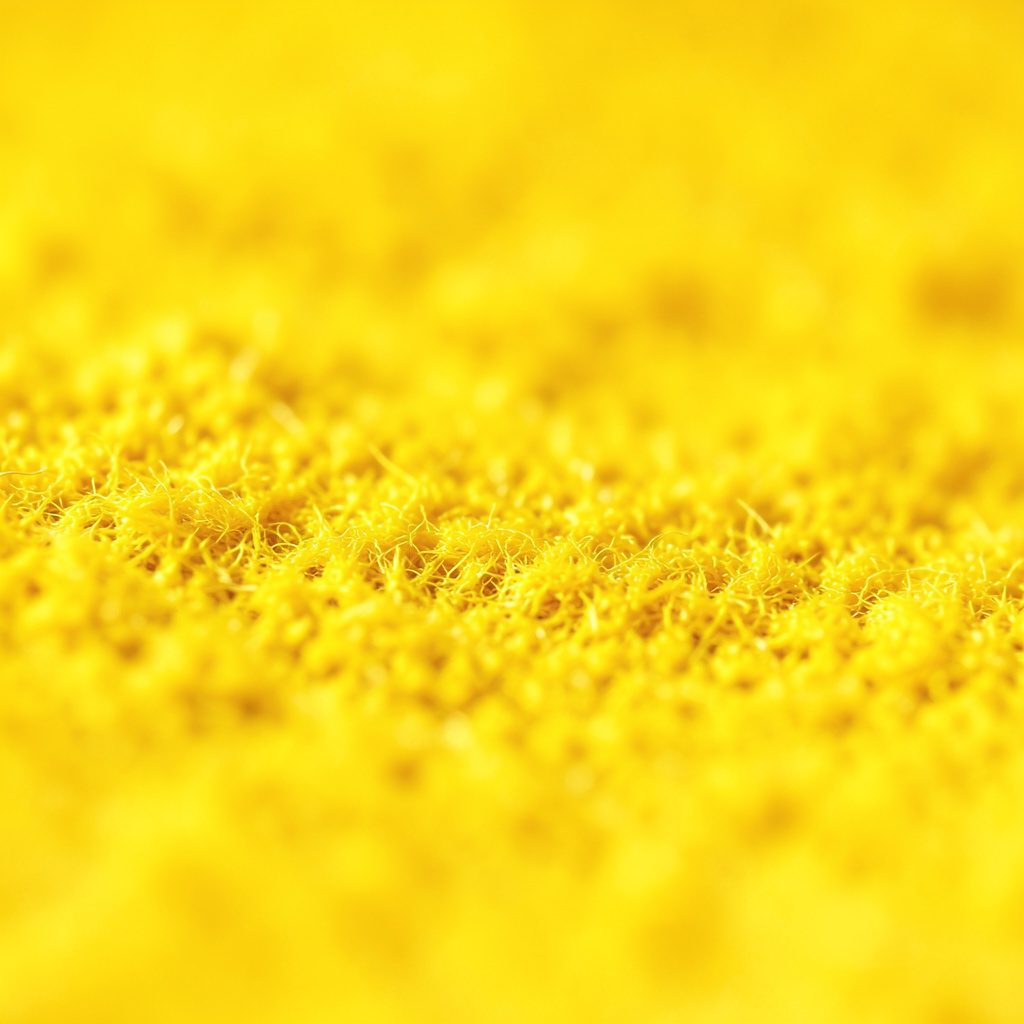 Superfície escura com textura de tecido tramado em tons de cinza e azul profundo, iluminada lateralmente por uma luz suave que revela os fios entrelaçados